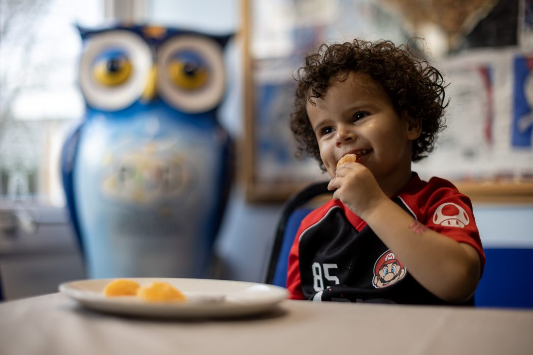 Young boy eating orange segment from a plate