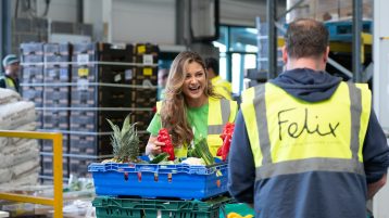 Woman holding peppers in warehouse in conversation with man
