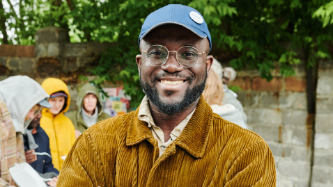 Man wearing cap and glasses smiling towards camera