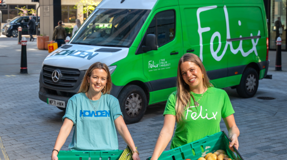 Two people standing in front of van holding crates of fruit and veg. One wearing a Howden t-shirt and one wearing Felix t-shirt