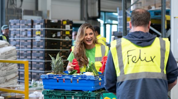 Woman holding peppers in warehouse in conversation with man