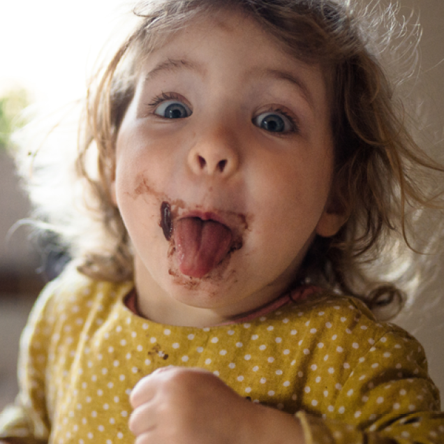 Girl in yellow polka dot shirt sticking her tongue out at the camera