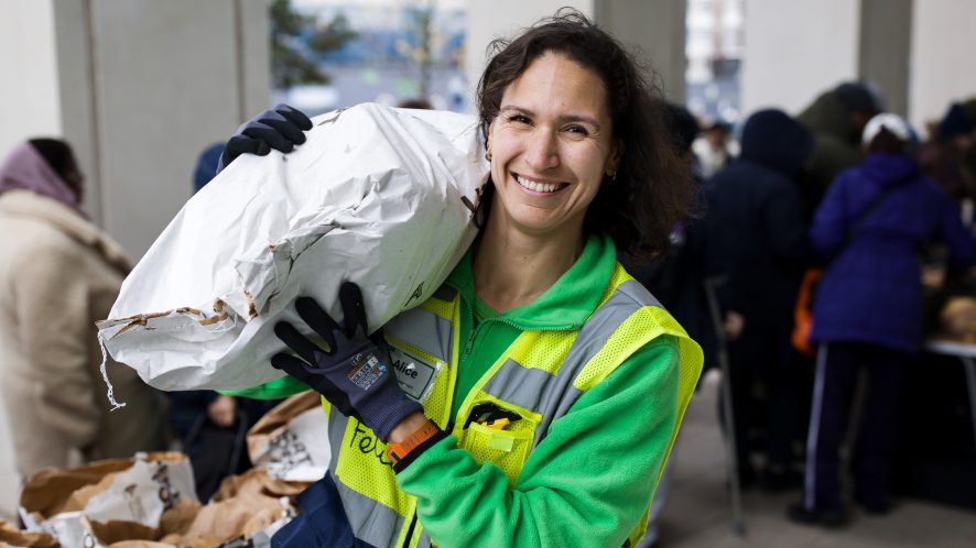 Woman in high-vis carrying sack of potatoes on her shoulder