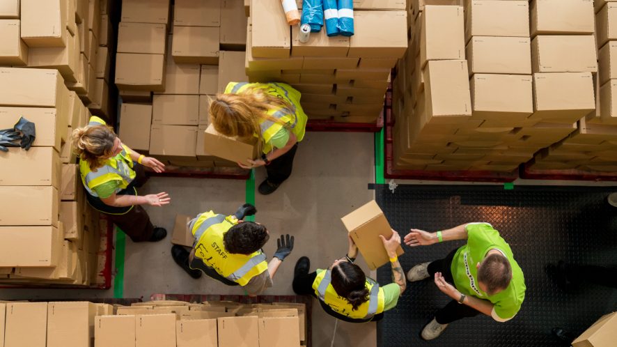 Top down shot of line of volunteers passing boxes of food and stacking onto pallets