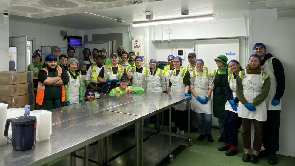 Group of people wearing aprons posing for shot in kitchen