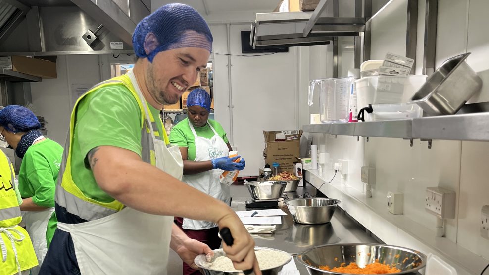 Man in hairnet and apron stirring big bowl of cake mix